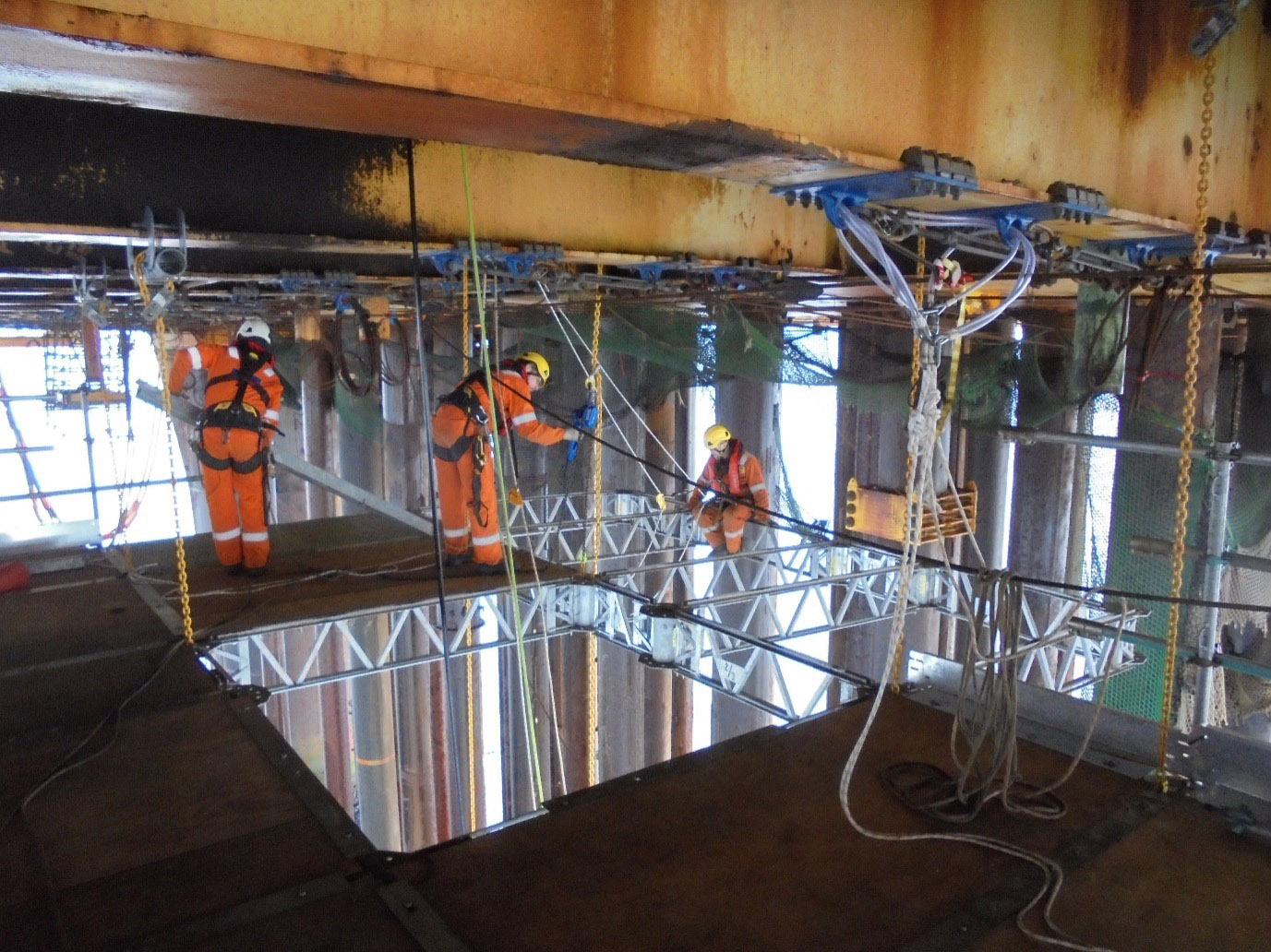 Three AquaTerra personnel using AquaTerra's QuikDeck suspended working platform to remove conductors on the Dunlin Alpha decommissioning project